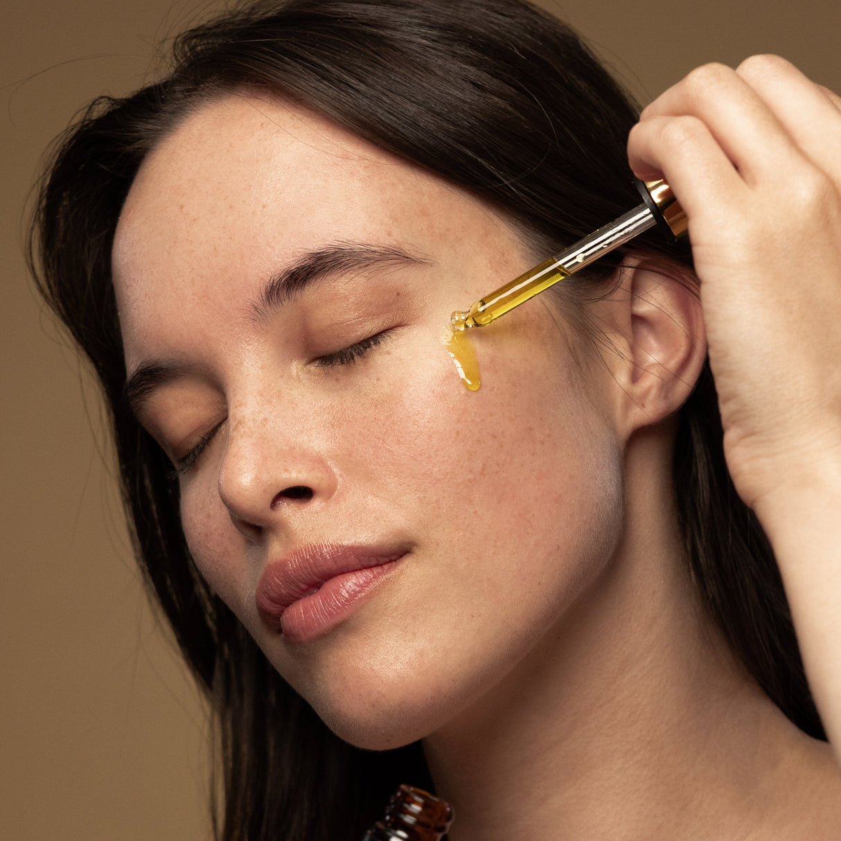 Model applying Antipodes rosehip and avocado face oil with dropper