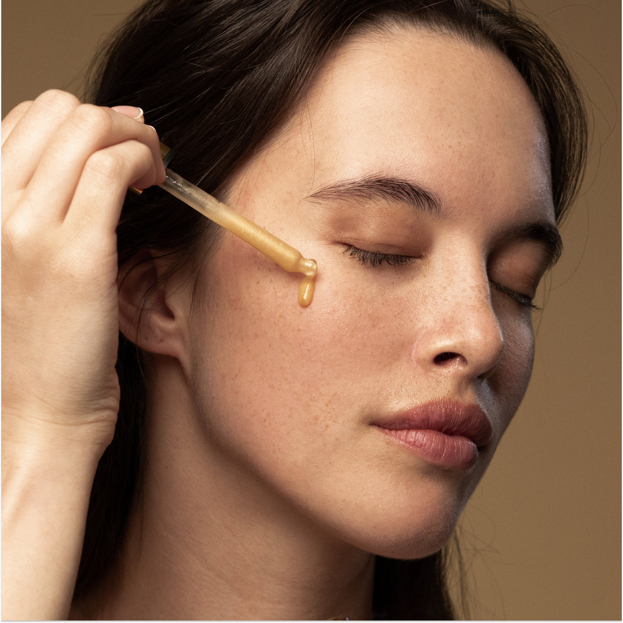 Model applying Antipodes Glow Vitamin C Serum with dropper on face