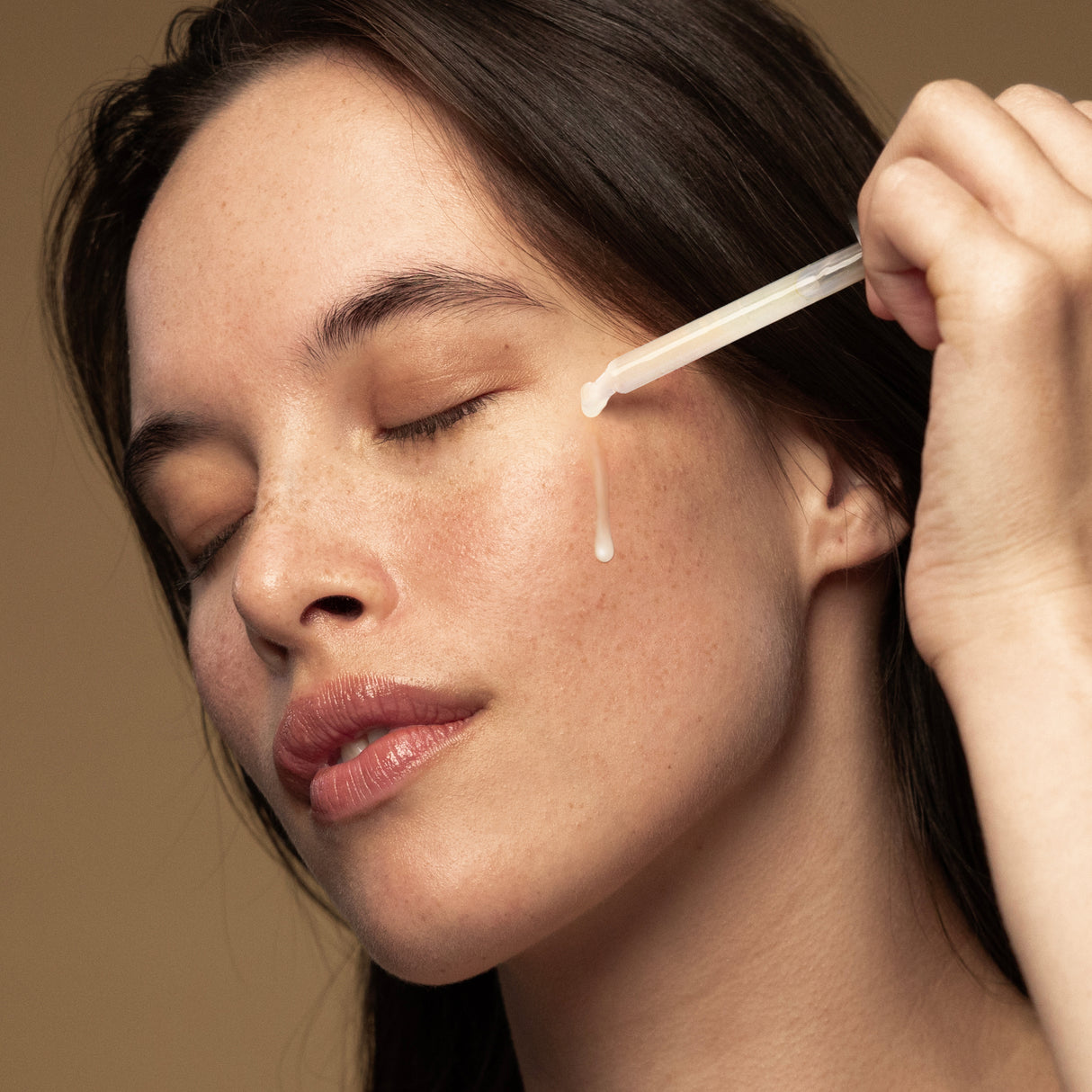 Model applying Antipodes Maya Hyaluronic Serum with dropper on face