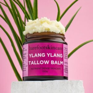 Barefoot Skincare Ylang Ylang Tallow Balm open jar with whipped texture and tropical leaves background