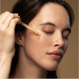 Model applying Antipodes Glow Vitamin C Serum with dropper on face