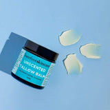 Barefoot Skincare Unscented Tallow Balm jar with scattered natural balm pieces on blue background