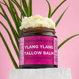 Barefoot Skincare Ylang Ylang Tallow Balm open jar with whipped texture and tropical leaves background